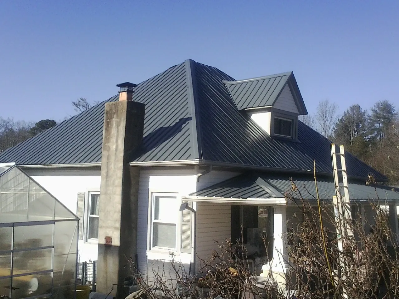Dark blue standing seam metal roof on a white farmhouse with dormer — Slate & Tile Roof Repair by Roofing Brothers in Olalla
