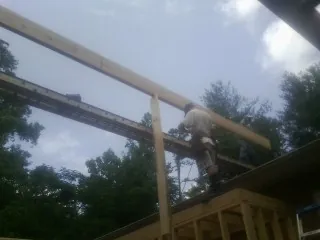 Carpenter setting a ridge beam over a new addition frame — Ice Dam Removal by Roofing Brothers in Olalla