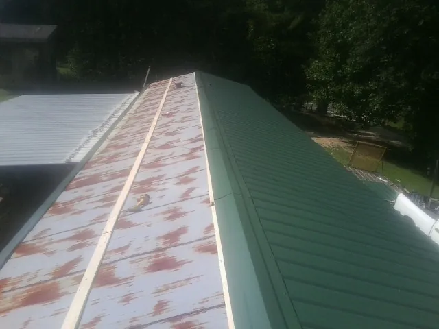 Old rusted panels beside newly installed green metal roofing — Wind Damage Roof Repair by Roofing Brothers in Olalla