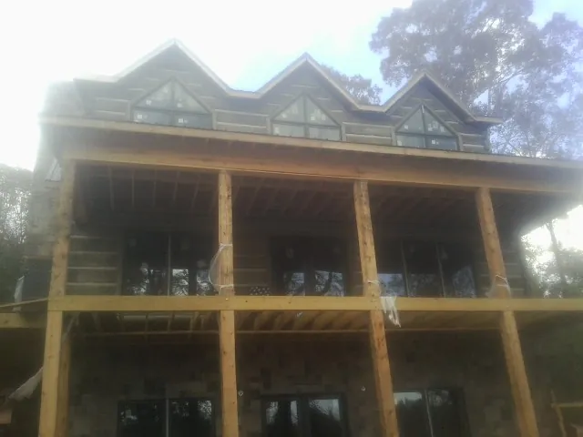 Dormers and porch framing on a large log home under construction — Roof Coating work by our crew in Olalla