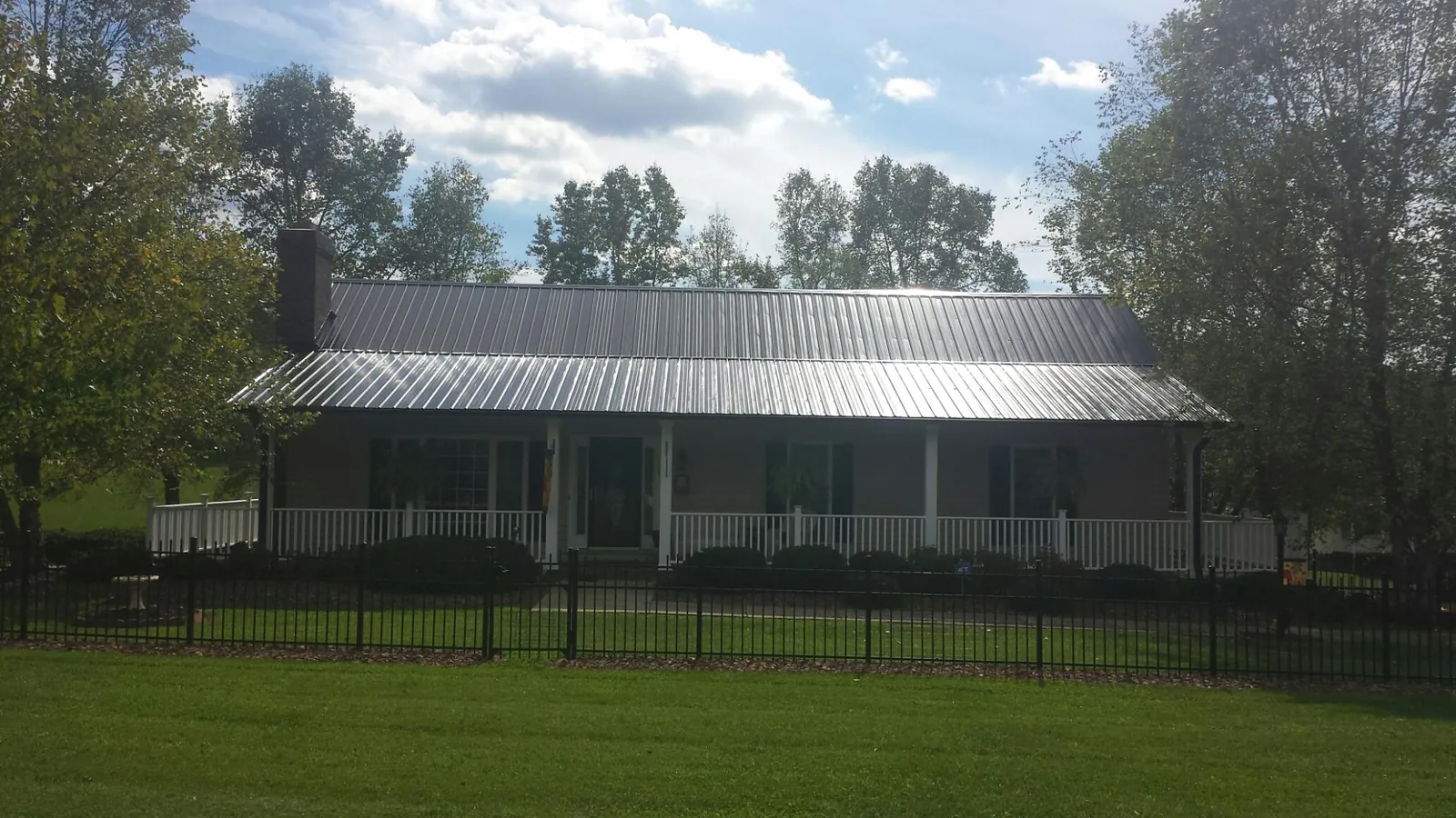 Gray metal roof on a brick ranch with a full width front porch — Gutter Guard Installation work by our crew in Olalla