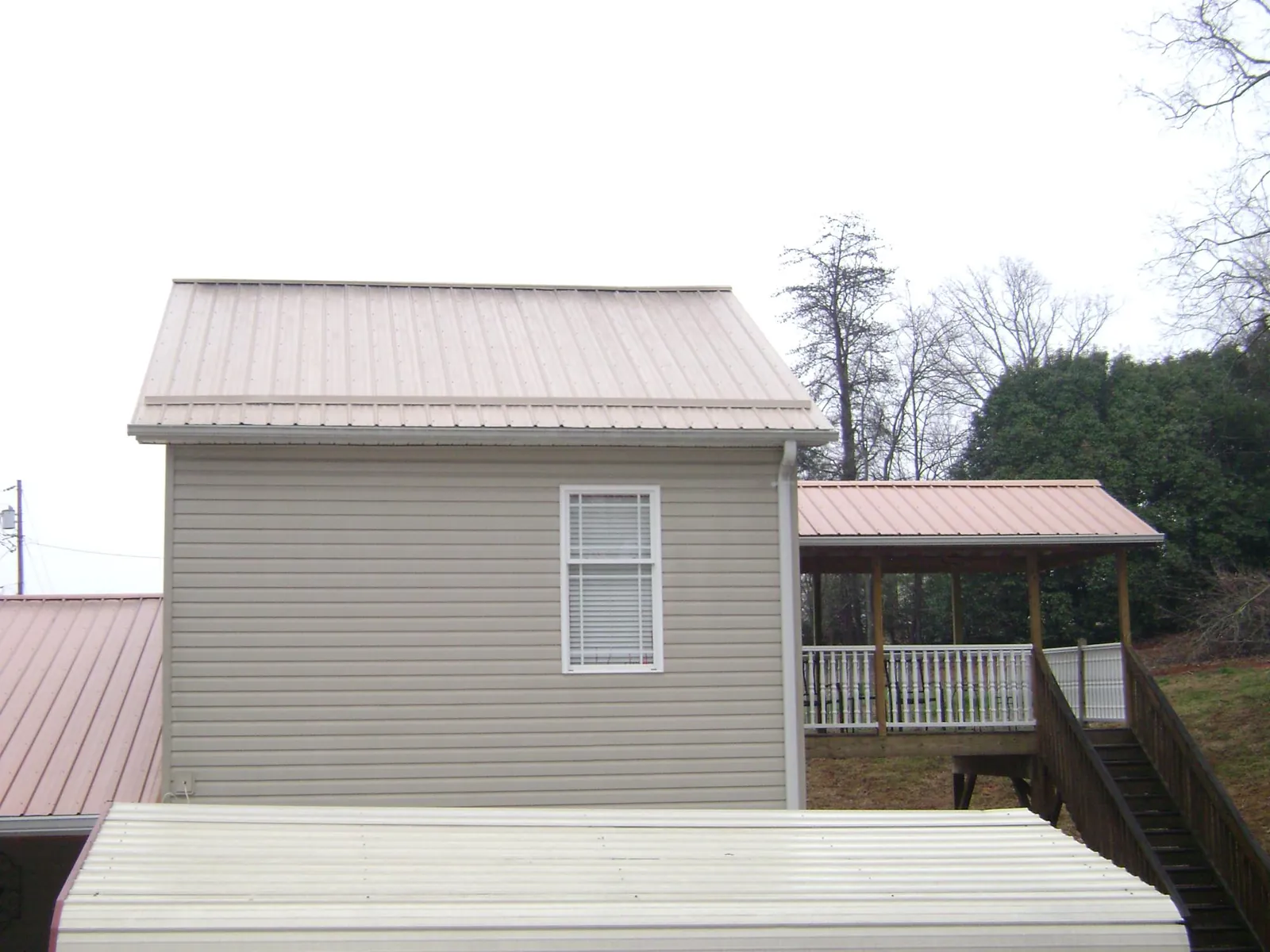 Tan metal roofs on a two story addition and attached porch, from a Roof Replacement job in Olalla