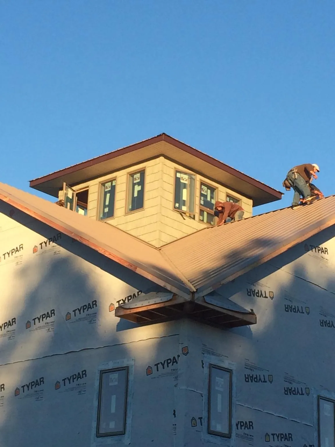 Roofers working around a rooftop cupola on a new metal roof at sunset — Roof Waterproofing in Olalla by Roofing Brothers